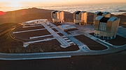 This image shows the Paranal plaftorm with the telescopes that make up ESO’s Very Large Telescope atop it. In the background we see clouds surrounding the Paranal mountain, and the setting sun on the left.