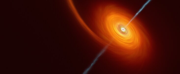 This image shows a bright spiral, against the dark background of space, that is a deep orange at the outer edges and towards the centre it becomes much brighter and closer to yellow or even white in colour. At the very centre is a black hole from which jets of white-blue wisps shoot out. These jets are coming out of both poles of the black hole and are perpendicular to the spiral disc.