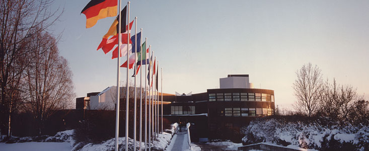 The ESO Headquarters building in winter during daytime. There is snow on the ground, the sky is blue and some of the Member States flags are flying in the foreground.