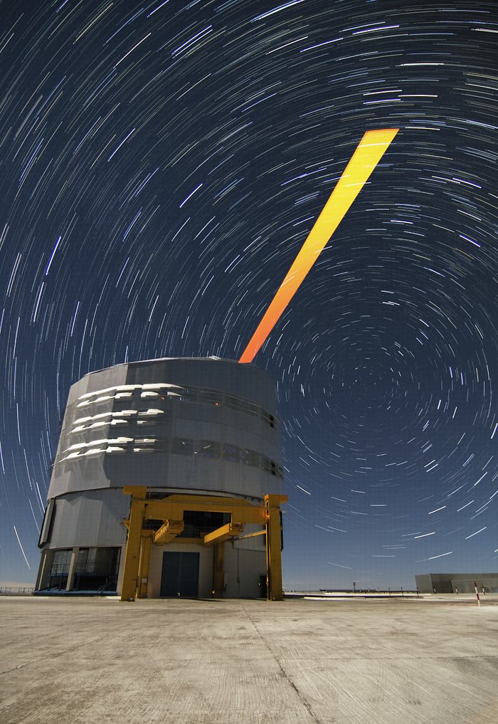 De ESO-sterrenwacht op Paranal tegen een achtergrond van stersporen en de VLT-laserbundel